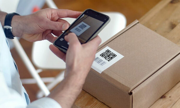 The employee is scanning a qr code label on a product to obtain detailed information about that product